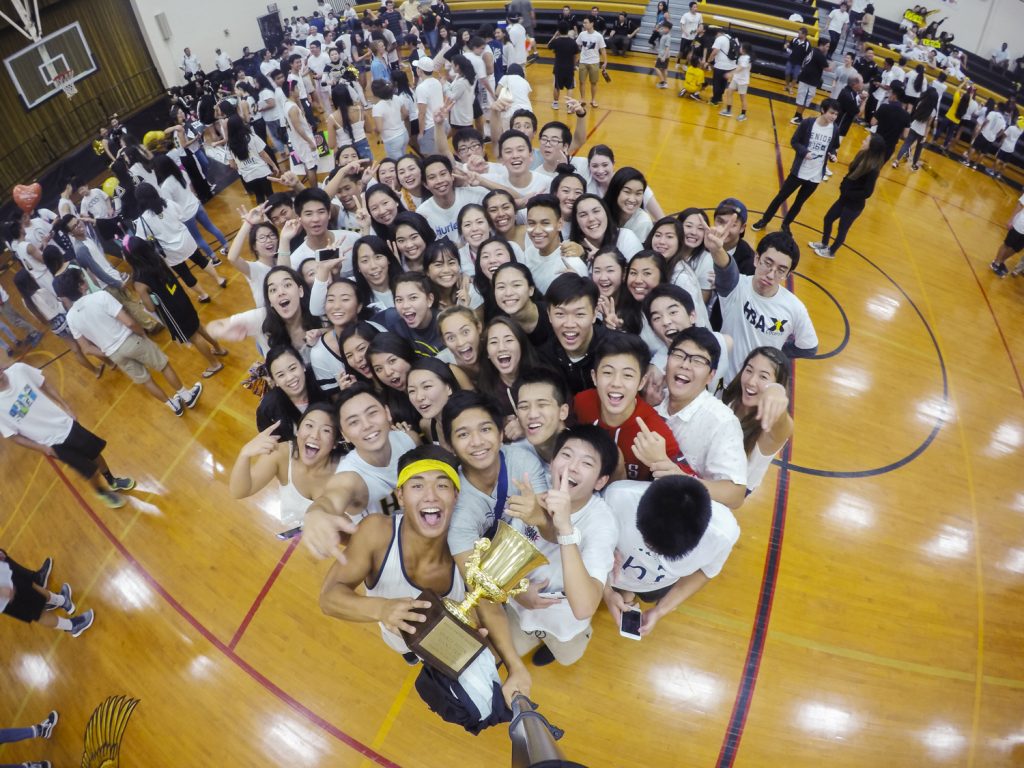 Day 5: At the basketball Homecoming Game that evening, the seniors were announced as the winners of Spirit Week. Coming together as a class, the seniors hoist the Mana Cup for a class selfie. Photograph by Logan Takeda.
