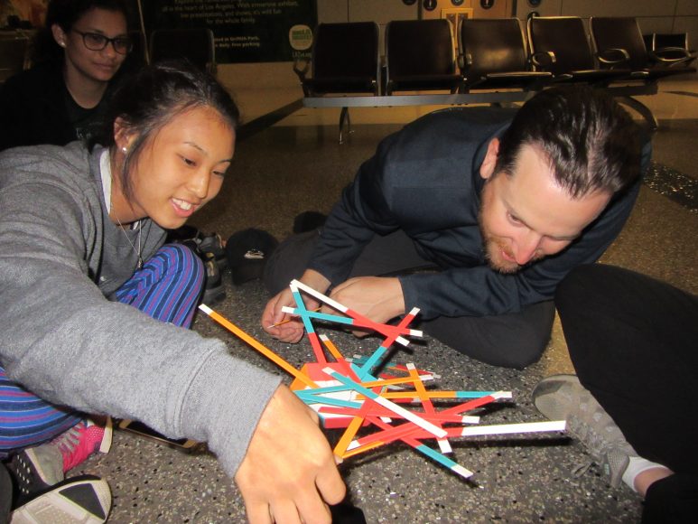 The group plays an intense game of stick stack at the LAX airport.